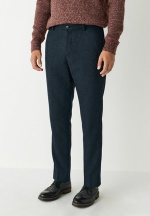 Dunkelblaue Fischgrät-Hosen mit einer taillierten Passform, aus strukturiertem Stoff gefertigt. Mit einem Knopfverschluss und vorderen Taschen.