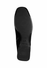 Black suede shoe sole with a textured rubber surface. Features a circular logo and the brand name "Toms" embossed on the side.