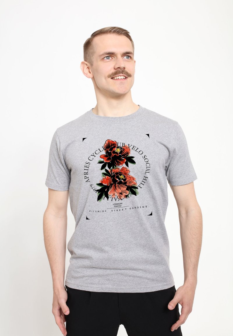 Camiseta de algodón gris con un diseño gráfico floral en rojo y verde, centrado en el pecho con elementos de texto en negro. Mangas cortas.