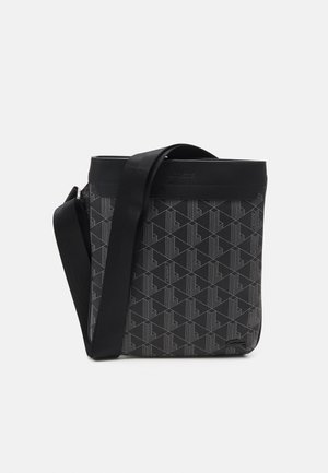 Sac bandoulière noir avec motif géométrique, sangle réglable et nom de marque embossé sur le bord supérieur et le coin inférieur.