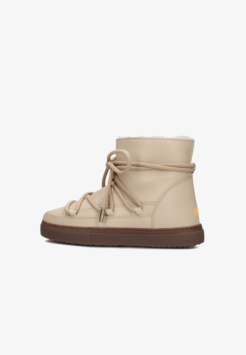 Beige ankle boot crafted from smooth leather, featuring a soft faux fur lining, rounded toe, decorative laces, and a textured brown sole.