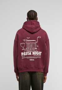 Felpa in cotone bordeaux con una grafica umoristica di pasta e utensili da cucina sulla schiena, con testo bianco che recita "Pasta Night."