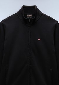 Schwarze Zip-Jacke aus glattem Stoff mit hohem Kragen und einem kleinen roten und weißen Logo auf der linken Brust.