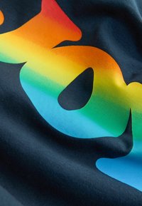 Vaivorykštės gradiento užrašas ant tamsios medžiagos, spalvos pereina nuo raudonos iki mėlynos per ryškią, išlinkusią formą.