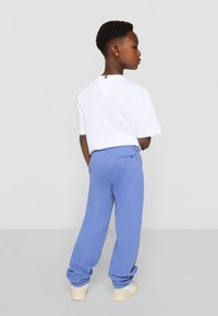 White short-sleeve T-shirt paired with light blue sweatpants with a back pocket, featuring an elastic waistband and ribbed cuffs.