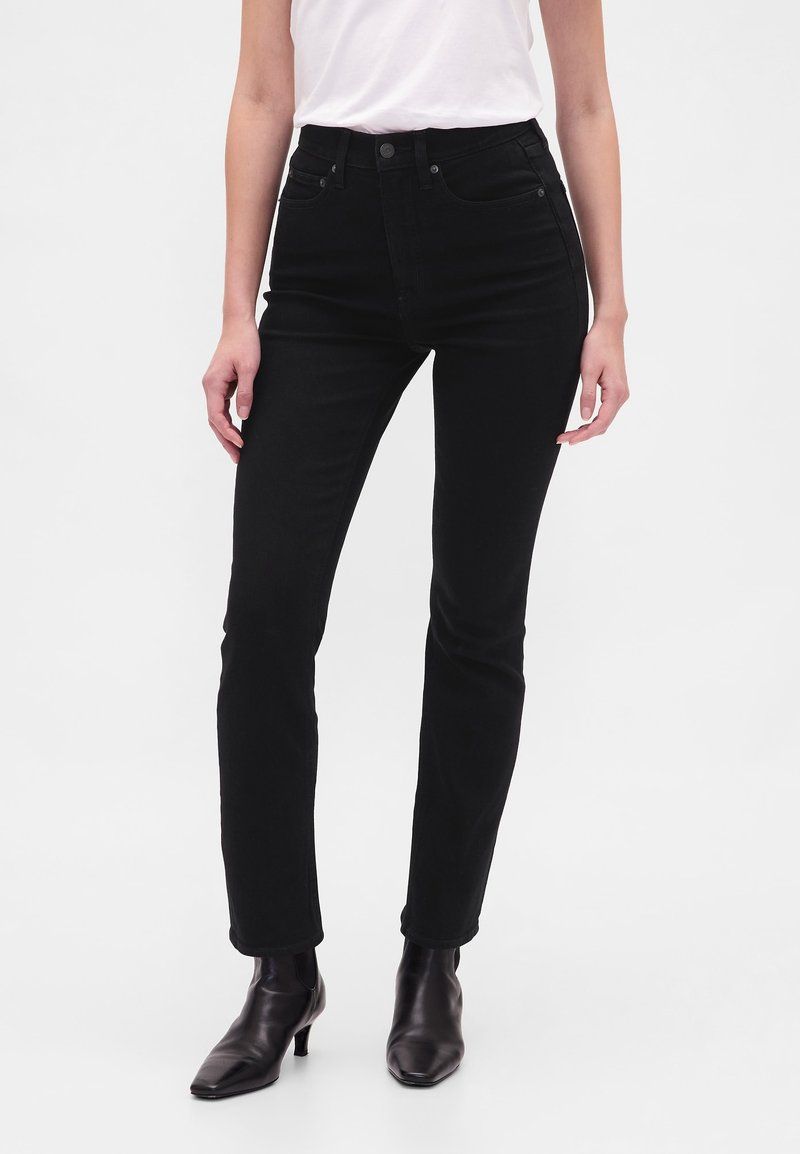 Črne jeans hlače z visokim pasom v ozkem kroju, izdelane iz jeansa. Vsebujejo pet žepov, sprednjo zapenjavo na gumbe in subtilne šive.