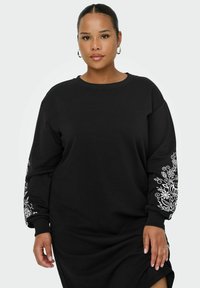 Czarna sukienka z bluzy z długimi rękawami, ozdobiona białym kwiatowym haftem na rękawach. Wykonana z miękkiego materiału, o luźnym kroju i okrągłym dekolcie.