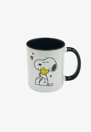 Weißer Keramikkrug mit schwarzem Innenraum und Griff. Zeigt eine Grafik eines Cartoon-Hundes, der einen Vogel umarmt, mit roten Herzen über ihnen.