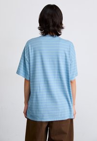 Blå stribede T-shirt med korte ærmer og en afslappet pasform, lavet af bomuld, som har subtile lysegrønne striber på stoffet.