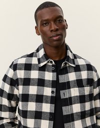 Fekete-fehér kockás flaneling, gallérral, gombos elejével és mellzsebbel. Az anyag puha, textúrált megjelenésű.