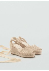 Beige espadrille wedges with woven rope upper, open back, and a soft ribbon ankle tie. Textured platform sole and rounded toe.