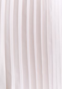 Tessuto a pieghe di un delicato rosa, caratterizzato da linee verticali con una consistenza liscia. Il materiale presenta una lucentezza sottile e un motivo uniforme in tutto.