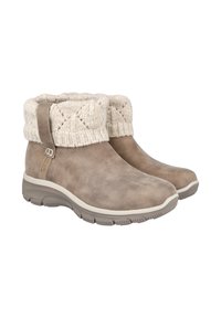 Botas de ante color marrón claro hasta el tobillo, con suelas de goma gruesas y puños de color crema de punto doblados sobre la parte superior.