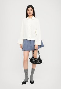 Valge nööbitav särk, helesinine ruuduline mini-seelik, hallid põlvini sokid, must studidega käekott, mustad terava ninaga kingad.