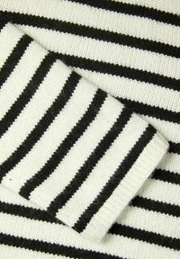 Tissu tricoté rayé en noir et blanc ; présente des rayures horizontales alternant entre épaisses et fines avec une texture douce.