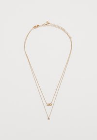 Collana in tono oro con due catene sovrapposte. Presenta un accento a forma di cuore e un piccolo pendente circolare. Texture liscia, maglie sottili.