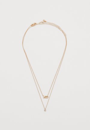 Gouden ketting met twee gelaagde kettingen. Beschikt over een hartvormige accent en een kleine ronde hanger. Gladde textuur, fijne schakels.