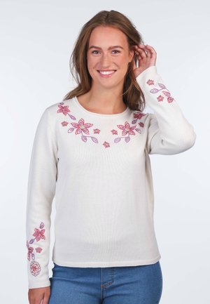 Weißer Pullover mit floralen Stickereien in Rosa und Lila, mit langen Ärmeln und rundem Ausschnitt, kombiniert mit blauen Jeans.