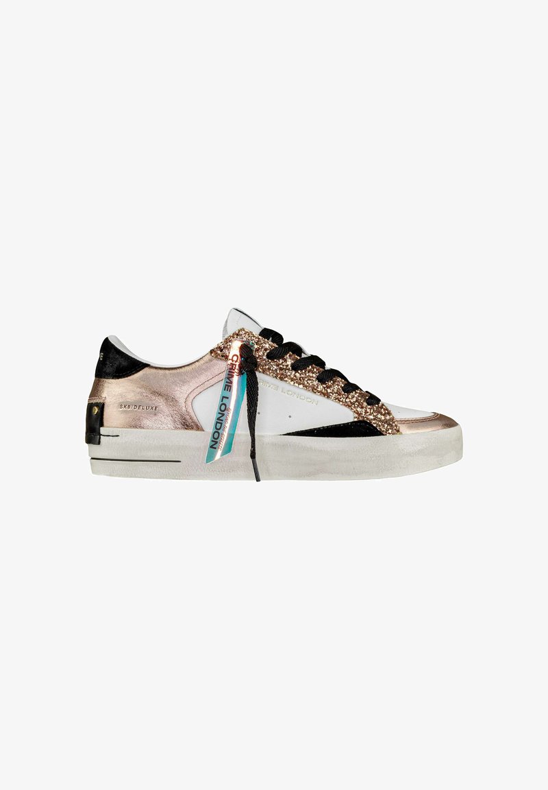 Zapatilla con parte superior de piel blanca, detalles en ante negro y adornos de purpurina de color rosa dorado. Incluye cordones negros y una etiqueta colorida.