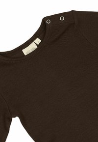 Braunes Langarmshirt mit geripptem Muster, ausgestattet mit zwei silbernen Druckknöpfen an der Schulter und einem runden Ausschnitt. Etikett ist innen sichtbar.