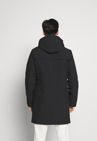 Svart vanntett parkas med hette, med en lang design og minimale sømmer, laget av strukturert stoff, med en rett passform.