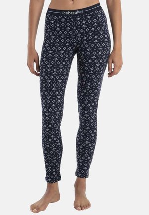 Barefoot person wearing navy blue patterned leggings with a geometric white diamond design and an icebreaker logo waistband.