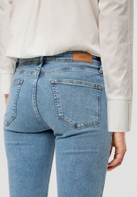 Lichtblauwe denim jeans met een aansluitend ontwerp. Beschikt over vijf zakken, subtiele stiksels en een bruine leren label op de achterzijde van de taille.
