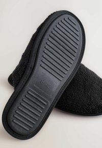 Svarta textilsandaler med en fluffig textur. Tjock gummisula med horisontella skåror, storlek 8/42 markerad på undersidan.