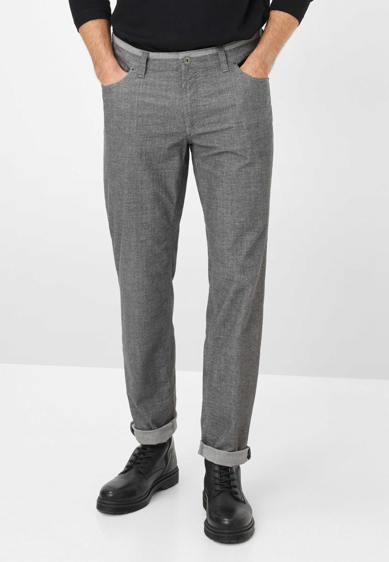 Grijze patroonbroek van lichtgewicht stof, met een rechte pijp, opgerolde manchetten en zijzakken, gecombineerd met zwarte laarzen.