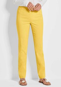 Gele katoenen broek met een slim fit, voorzien van voorzakken en een gladde textuur. Gepaard met lichtbruine sandalen met een ronde acccent.