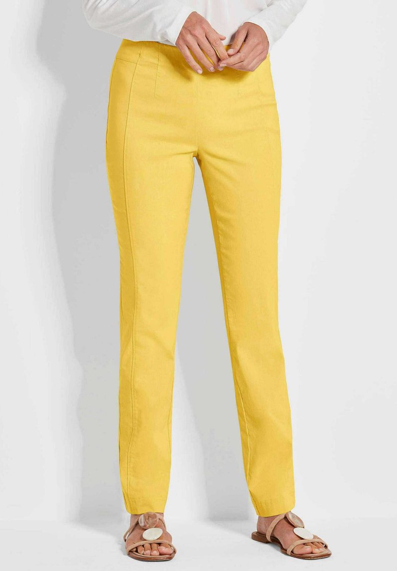 Gele katoenen broek met een slim fit, voorzien van voorzakken en een gladde textuur. Gepaard met lichtbruine sandalen met een ronde acccent.