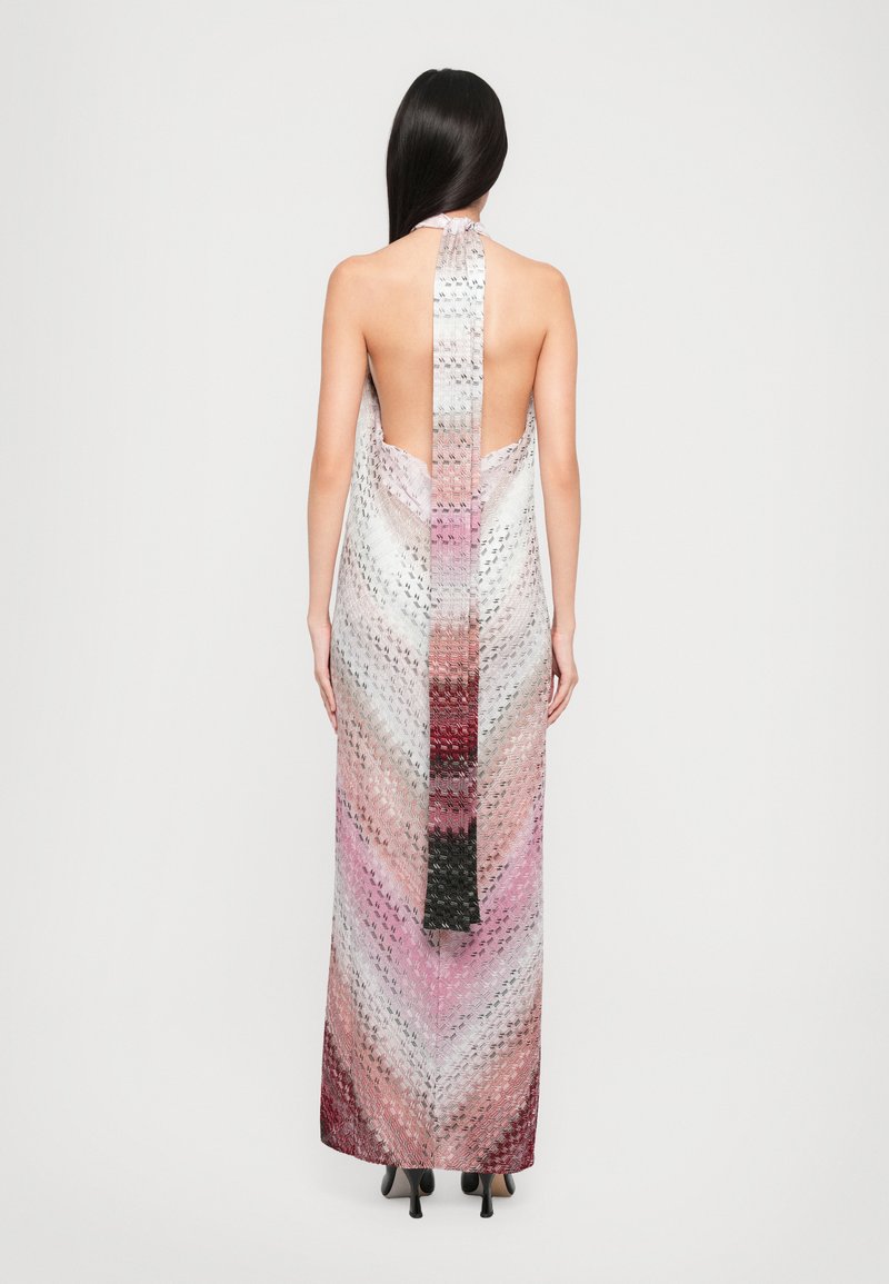 Robe longue à col halter avec un dos ouvert, présentant un motif en chevrons dans des dégradés de rose, blanc et noir. Tissu lisse et léger.