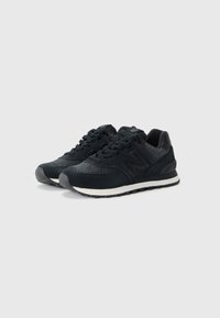 Czarne sneakersy z teksturowaną cholewką, siateczkowymi detalami i grubą białą podeszwą środkową. Posiadają sznurowadła, gumową podeszwę oraz wytłoczone logo.