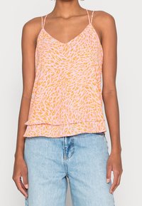 Roze en oranje camisoletop met dunne verstelbare bandjes, gelaagde zoom en een zachte, lichte stof. Gecombineerd met lichtblauwe spijkerbroek.