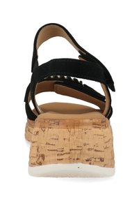 Zwarte suède sandaal met verstelbare banden, kurken wiggenhak en een gewatteerde voetbed voor comfort. Getextureerde zool zorgt voor grip.