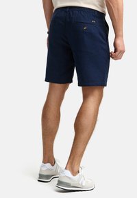 Navy blue shorts made of breathable fabric, featuring an elastic waistband, side pockets, and subtle back buttoned pockets.