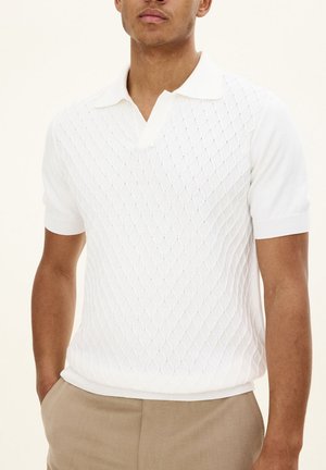 Polo shirt bianco a maglia con motivo a diamante, maniche corte e colletto piatto. Tessuto testurizzato con bordi a coste.