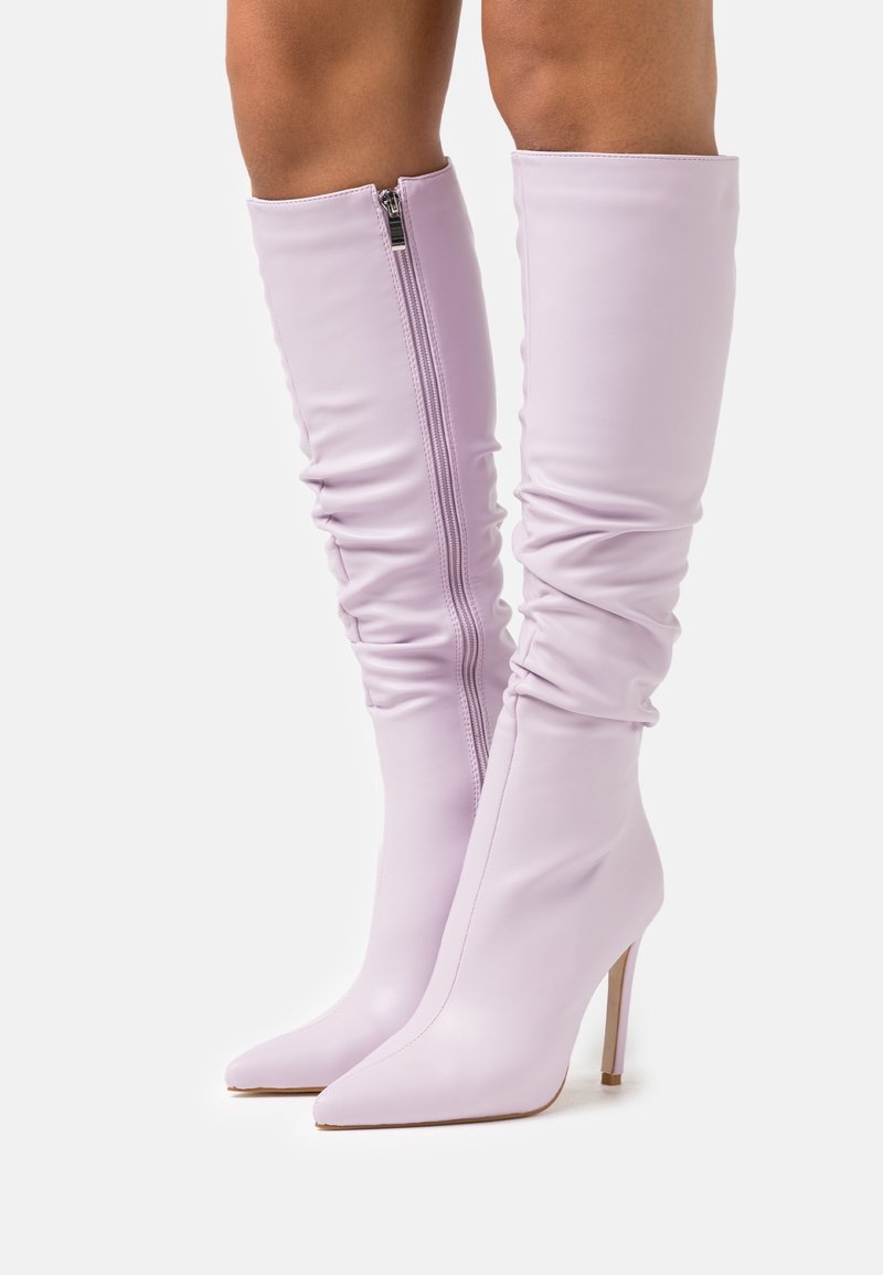 Bottes hauteur genou lilas en matière synthétique lisse, avec un bout pointu, un talon stiletto haut et une fermeture éclair latérale avec un effet froncé.