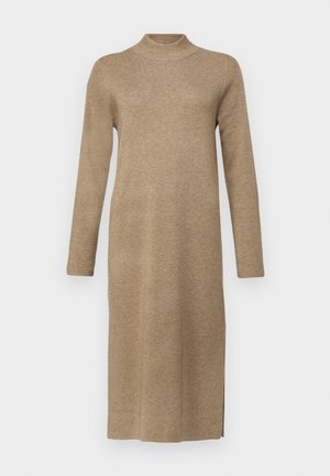 Langærmet strikkjole med høj hals i lys brun. Har en lige pasform med sideslids, blød tekstur og ensartede sting overalt.