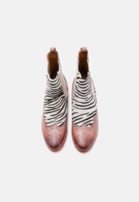 Ζευγάρι μποτάκια αστραγάλου με καφέ δερμάτινες μύτες και ασπρόμαυρο ζεβρέ μοτίβο στο πάνω μέρος, σε λευκό φόντο.