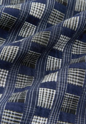 Marineblauer Stoff mit einem strukturierten Karomuster in Weiß und Schwarz. Weiches, gewebtes Material mit sichtbaren Nähdetails.