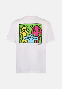 T-shirt bianco in cotone con una grafica colorata sul retro che presenta figure gialle, rosa e blu su uno sfondo verde, contornate in nero.