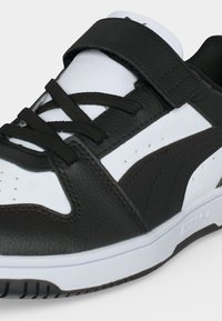 Μαύρο και άσπρο αθλητικό παπούτσι Puma χαμηλού προφίλ με μαύρα κορδόνια, μαύρο λουράκι στο πάνω μέρος και το λογότυπο Puma στη λευκή σόλα.