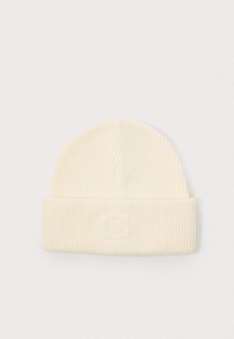 Geribde crèmekleurige beanie met een omgeslagen rand en een reliëflogo op de voorkant. Zachte textuur, gebreide stof en een afgeronde topvorm.