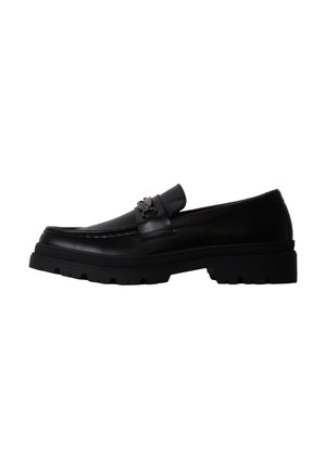 Mocassin en cuir noir avec semelle épaisse et détail mors métallique, vu de profil sur fond blanc.