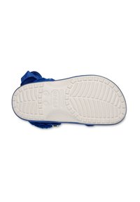 Sohle eines blauen Crocs-Schuhs mit sichtbarem weißen, strukturierten Profilmuster sowie Größen- und Markendetails.