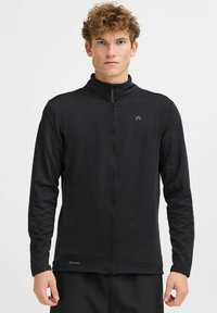 Giacca nera con zip realizzata in tessuto testurizzato. Caratterizzata da un colletto alto, maniche lunghe e un logo vicino alla zip. Materiale ad asciugatura rapida.