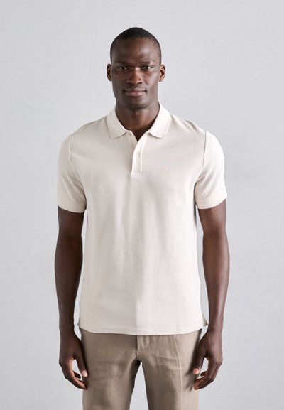 Polo beige in cotone con pattina a tre bottoni e maniche corte. Presenta un logo sottile sul petto e tessuto uniforme.
