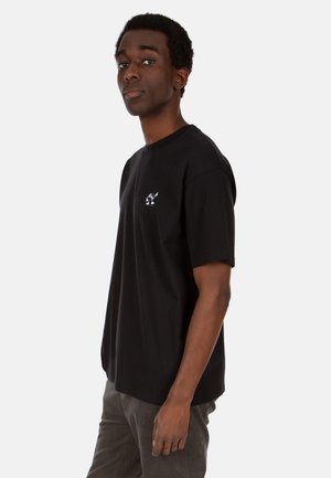 Schwarzes Baumwoll-T-Shirt mit kurzen Ärmeln. Mit einem kleinen weißen Grafik auf der Brust. Klassischer runder Ausschnitt. Lässiger Schnitt.