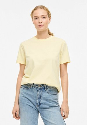 T-shirt jaune clair à manches courtes avec col rond, fabriqué dans un tissu doux, associé à un jean en denim bleu taille haute.